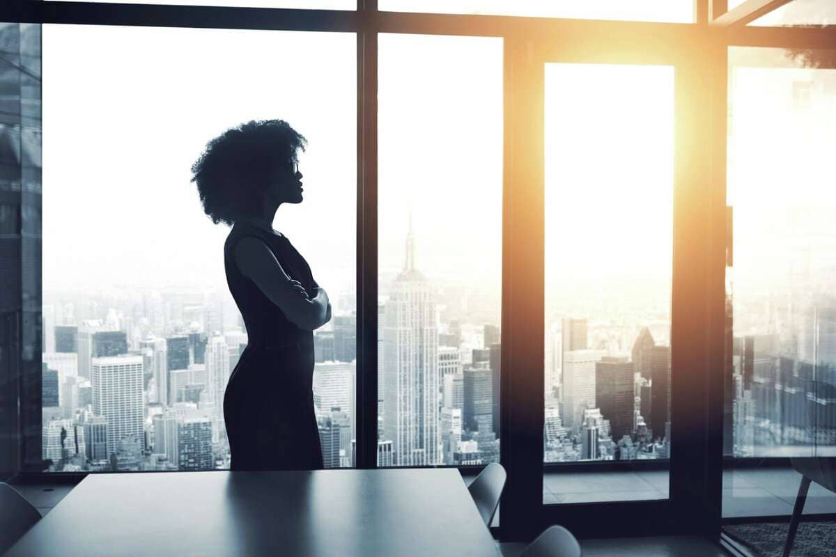 Black woman office worker with arms crossed as sun rises or sets